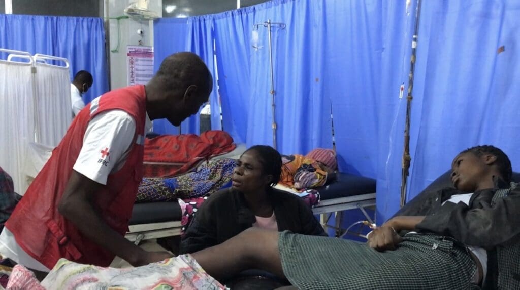 A Red Cross official comforts Mrs. Theresa Okrichi on the bedside of her daughter Oluchi Okrichi who was rescued from the ruins of the collapsed school. 