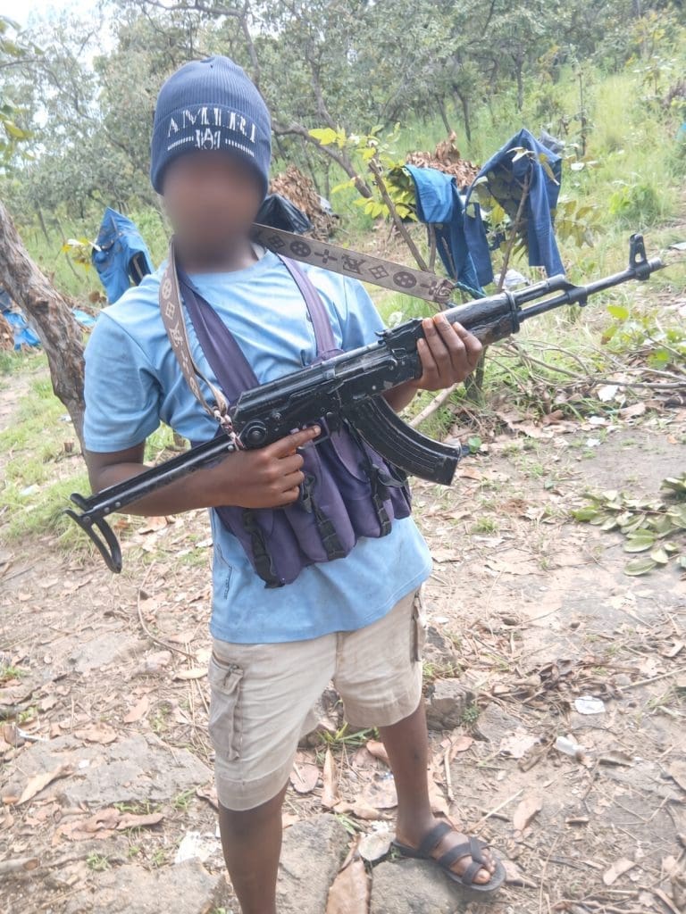 A 13-year-old boy poses with an AK 47 assault gun at a location in the bush after his abduction in September. Family claims the children were trained to become child-kidnappers. (Credit: distress family member).